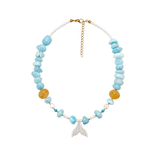 A beaded necklace featuring light blue stone chips, two amber-yellow beads, a silver mermaid tail charm, and a gold clasp, displayed on a clean white background.